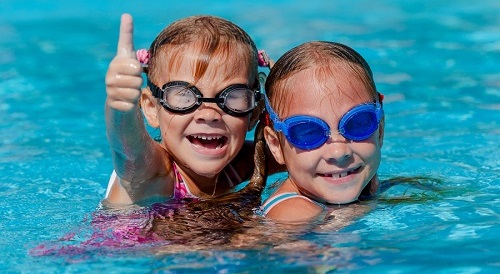 two happy little girls playing in the swimming pool